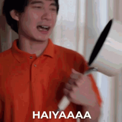 Man In Orange Shirt Holding Frying Pan GIF