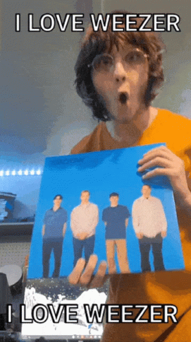 Man in Orange Shirt Holding Weezer Picture