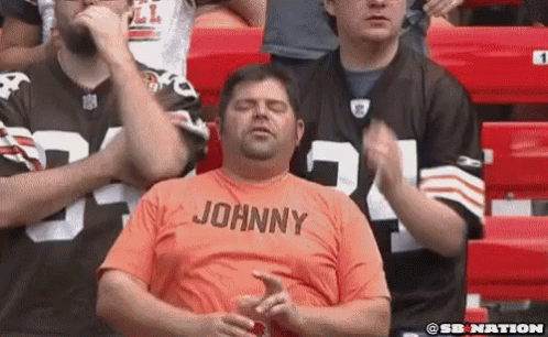 Man in Orange Shirt Johnny Sitting in Stadium