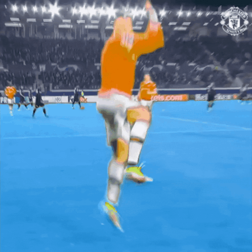 Man In Orange Shirt Running On Soccer Field With Manchester United Logo GIF