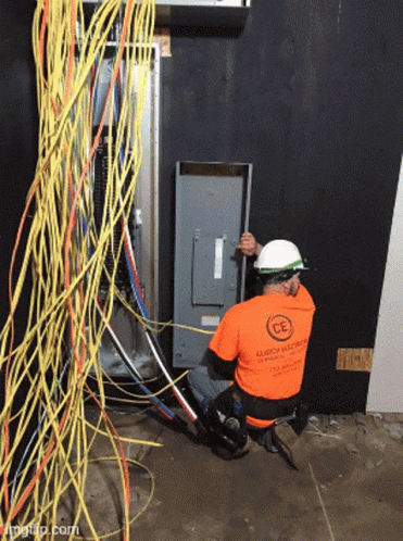 Man in Orange Shirt Saying CE Working on Electrical Panel