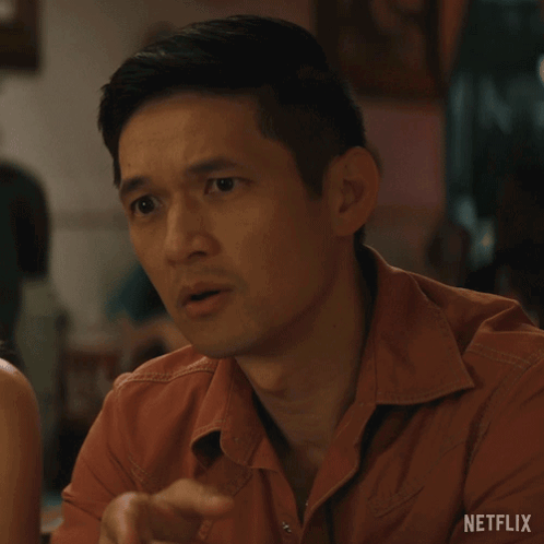 Man in Orange Shirt Sitting at Table With Netflix Logo