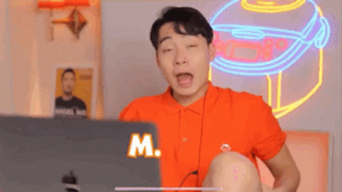 Man In Orange Shirt Using Laptop GIF