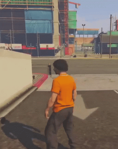 Man in Orange Shirt Walking in Front of San Building