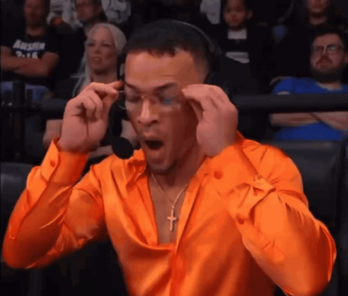Man in Orange Shirt with Cross Necklace and Headphones