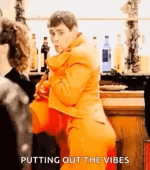 Man in Orange Suit Putting Out Vibes at Bar