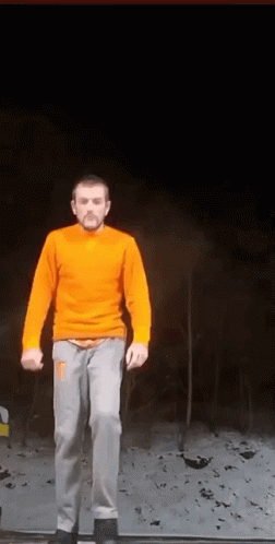 Man in Orange Sweater and Gray Pants on Ledge