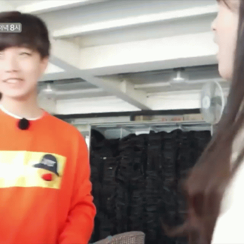 Man In Orange Sweatshirt Talking To Woman GIF