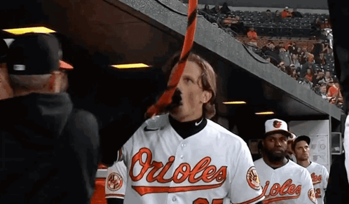 Man In Orioles Jersey Holding Bat In Mouth GIF