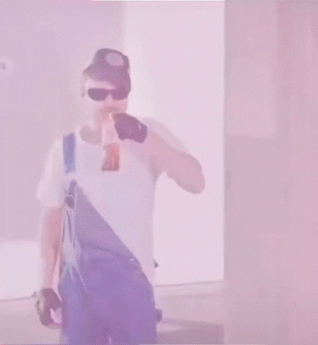 Man in Overalls and Blue Hat Holding Sword in Mouth