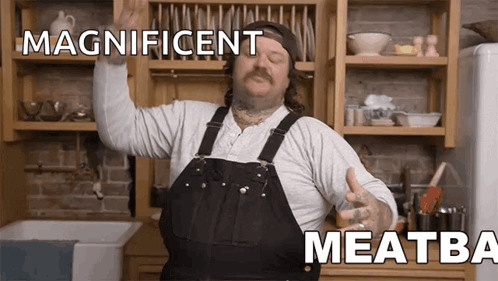 Man In Overalls In Kitchen With Arms In Air And Magnificent Meatba
