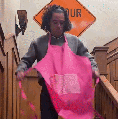 Man in Pink Apron in Front of Our Sign