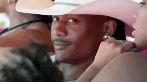 Man in Pink Cowboy Hat Sitting with Woman in Pink Dress