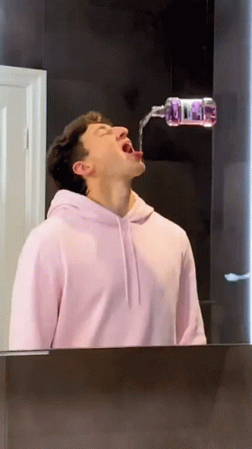 Man in Pink Hoodie Drinking From Bottle