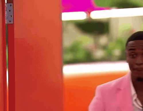 Man In Pink Jacket At Orange Door GIF