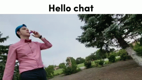 Man in Pink Shirt and Blue Hat Talking on Cell Phone in Front of Tree