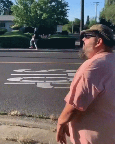 Man In Pink Shirt And Hat On Sidewalk GIF