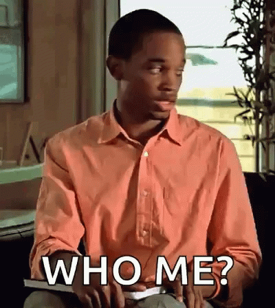 Man in Pink Shirt Holding Book Asking Who Me?