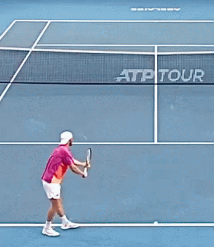 Man in Pink Shirt Holding Tennis Racquet in Crowd