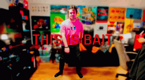 Man In Pink Shirt In Front Of Wall Saying This Vs Bait GIF