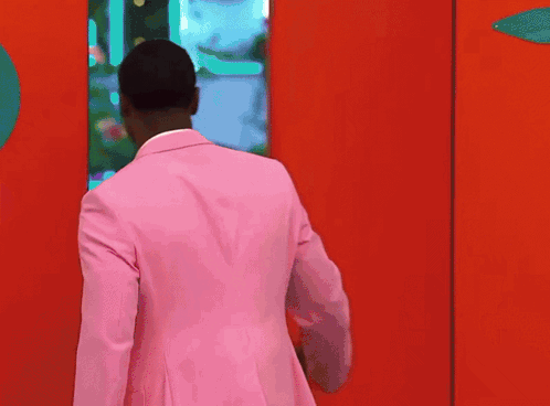 Man In Pink Suit In Front Of Red Door GIF