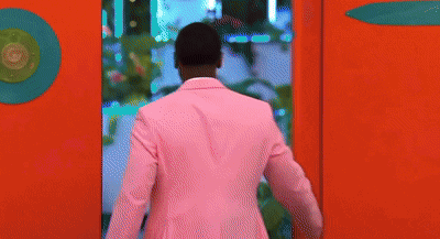 Man in Pink Suit Peeking Out of Red Wall