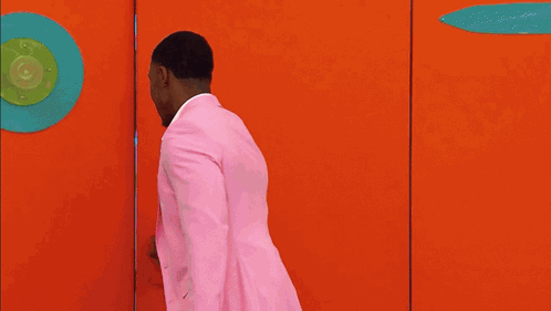 Man In Pink Suit Walking Through Doorway GIF