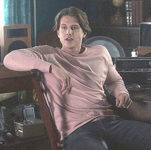 Man in Pink Sweater Sitting in Chair