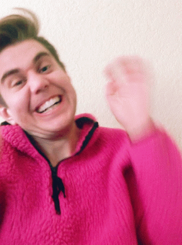 Man In Pink Sweater Smiling And Waving GIF