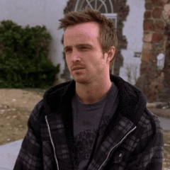 Man In Plaid Jacket And Gray Shirt Sitting Outside GIF
