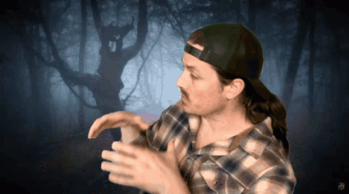 Man In Plaid Shirt And Cap In Front Of Tree GIF
