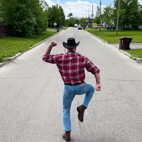 Man in Plaid Shirt and Cowboy Hat Standing on One Leg