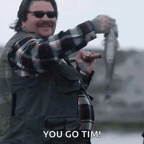 Man in Plaid Shirt Holding Fish and Fishing Rod