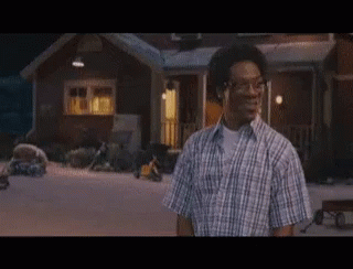 Man in Plaid Shirt in Front of House at Night