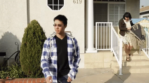 Man in Plaid Shirt in Front of House Number 619