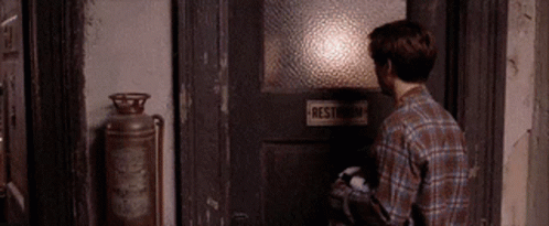 Man In Plaid Shirt Opening Restroom Door GIF