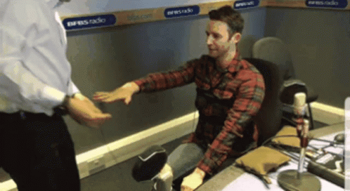 Man in Plaid Shirt Shaking Hands in Front of Express Radio Sign