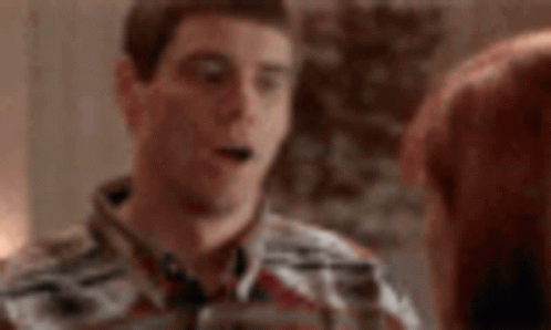 Man in Plaid Shirt Talking on Cell Phone Next to Woman