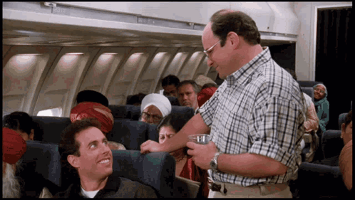 Man in Plaid Shirt Talking to Another Man on Plane