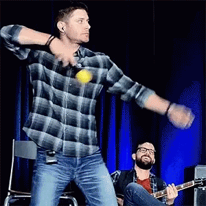 Man In Plaid Shirt Throwing Ball While Another Plays Guitar GIF
