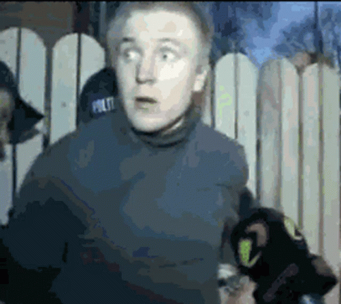 Man In Police Hat In Front Of Fence GIF