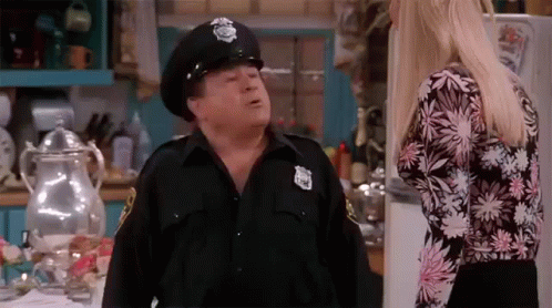 Man In Police Hat Talking To Woman In Kitchen GIF