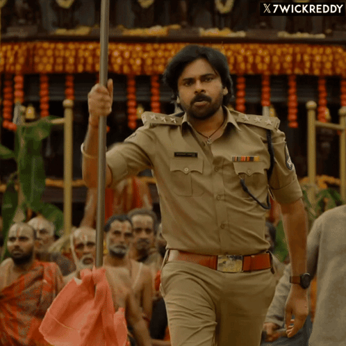 Man in Police Uniform Holding Pole in Crowd x7wickreddy