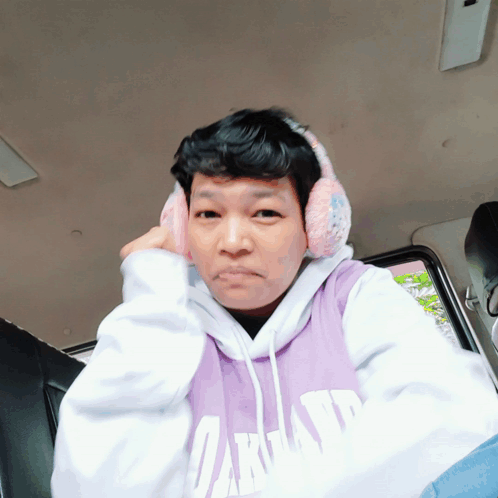 Man in Purple Oakland Sweatshirt and Ear Muffs