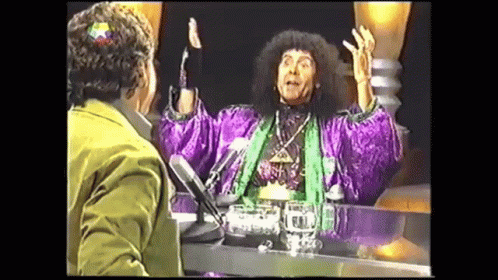 Man in Purple Robe Talking at Table With Microphone