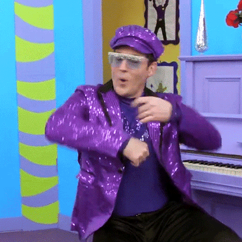 Man in Purple Sequined Suit Dancing by Piano