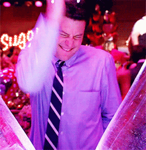 Man in Purple Shirt and Tie Smiling at Sugar Sign