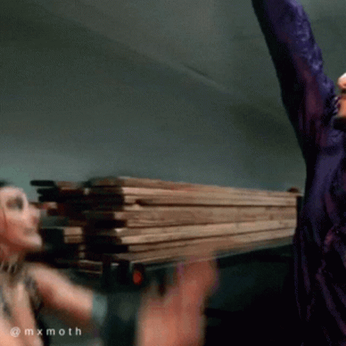 Man in Purple Shirt Holding Pile of Wood