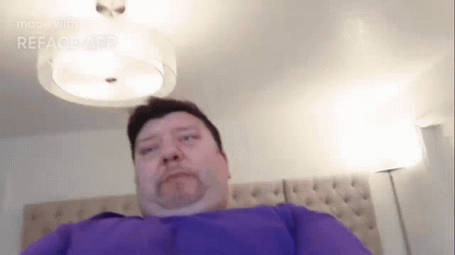 Man in Purple Shirt Laying on Bed
