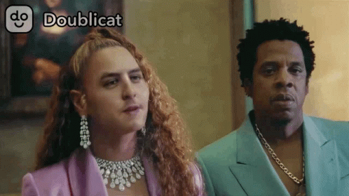 Man In Purple Suit Next To Woman With Necklace GIF